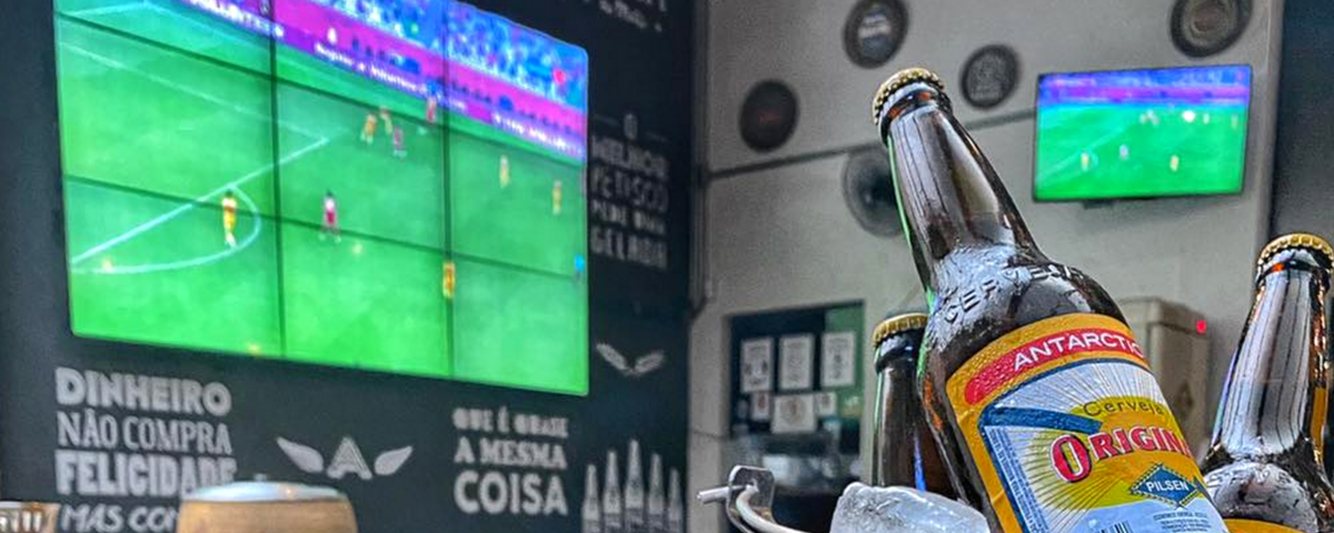 Telão ao fundo com Cerveja Original à frente, ilustrando o Dia Nacional do Futebol no Bar Figueiras.