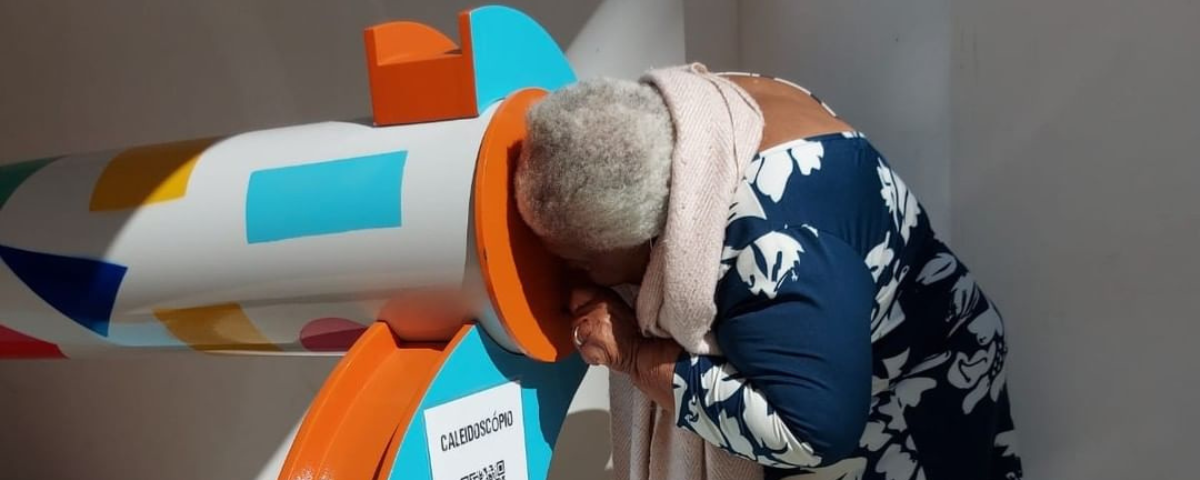 Pessoa inserindo a cabeça em um caleidoscópio, uma das atividades encontradas no CienTec.