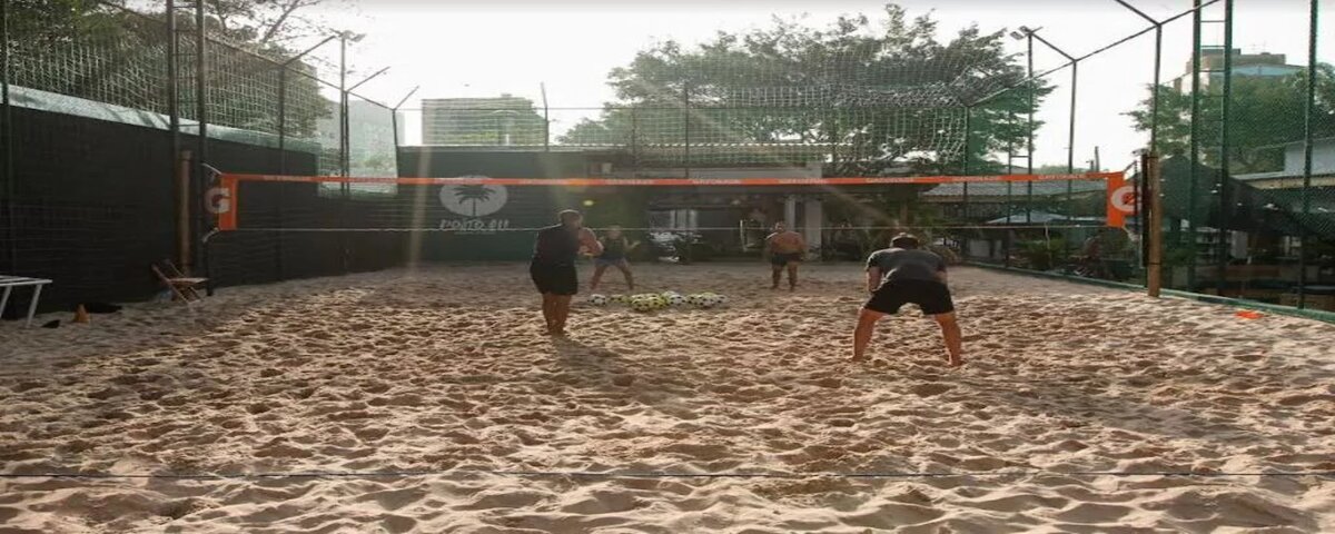 Quadra de areia do Posto 011, com 4 pessoas praticando algum esporte. 