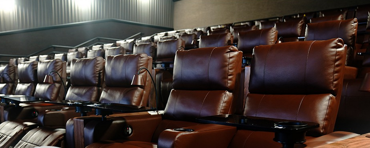 Foto da sala de cinema do Cinemark Bradesco Prime, uma opção de passeio no dia dos pais, com poltronas de couro marrom enfileiradas uma ao lado da outra.