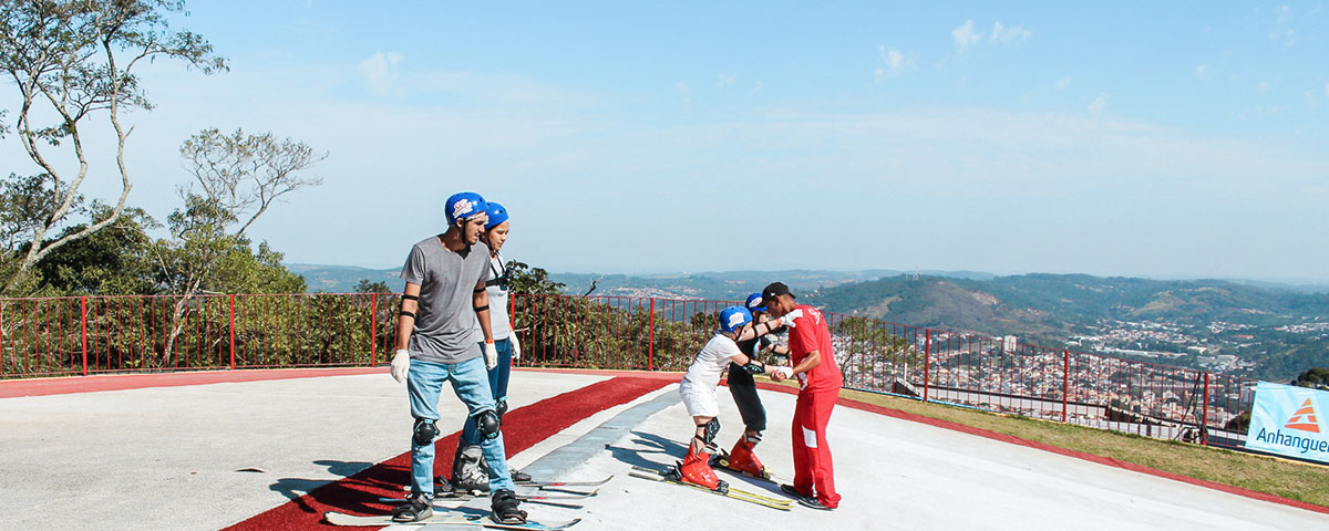 Pessoas no Ski Mountain Park, um dos parques de diversão da lista, com capacetes, pranchas de snowboard, esquis e equipamentos de segurança, se preparando para esquiar. 
