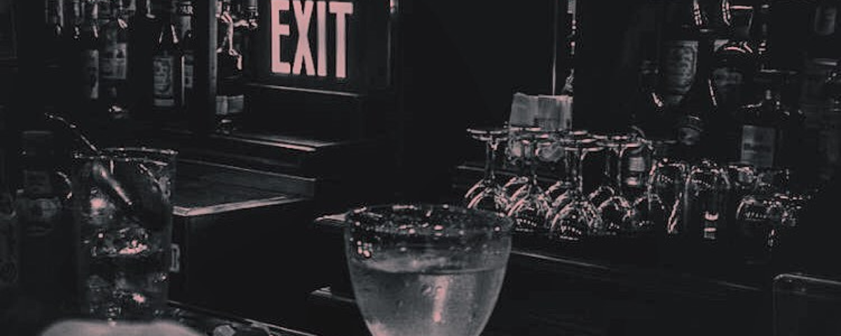 Foto em preto e branco do Exit bar, um dos bares secretos para ir em São Paulo, com drinks na mesa.