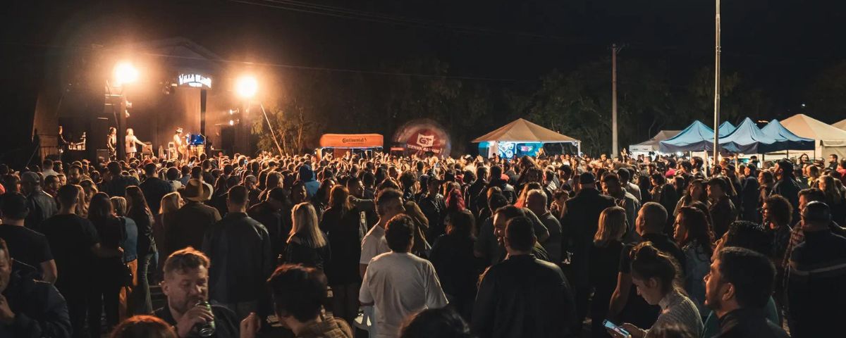 Foto de noite de um dos eventos Villa Blues Festival, um dos programas culturais a se fazer em agosto, com muitas pessoas em pé. 