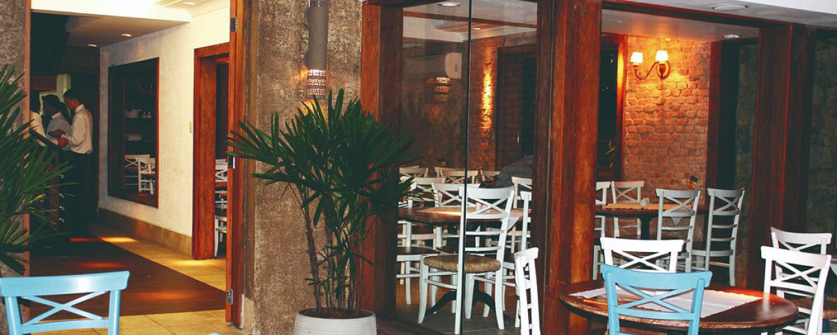 Interior do restaurante Graça Mineira, com cadeiras, mesas e vasos de plantas.