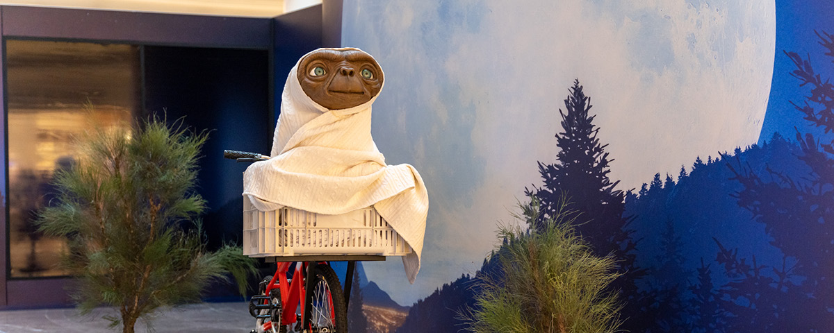 Foto da cena clássica do filme E.T, com o alienígena em cima da bicicleta. Essa é uma das representações que se encontra na exposição E.T.