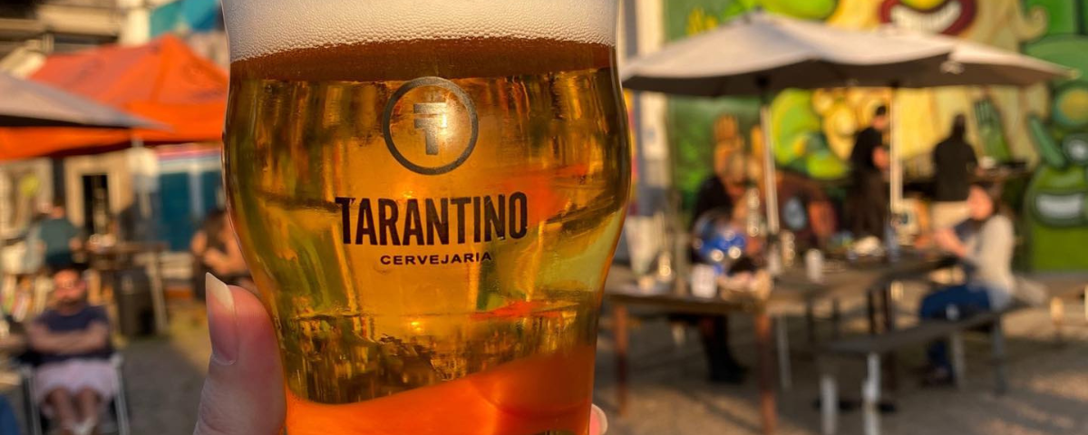 Foto de um copo de cerveja com o logo da Cervejaria Tarantino, um dos lugares para todo cervejeiro conhecer em São Paulo.