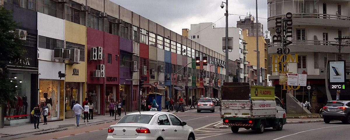 Centro comercial do Bom Retiro, com carros na rua e lojas no lado esquerdo da imagem.