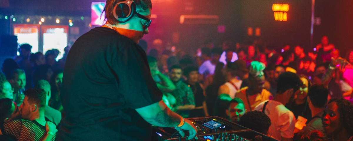 Foto da balada Selva, um dos lugares para passar o Dia das Bruxas, com pessoas dançando na pista e um DJ de costas.