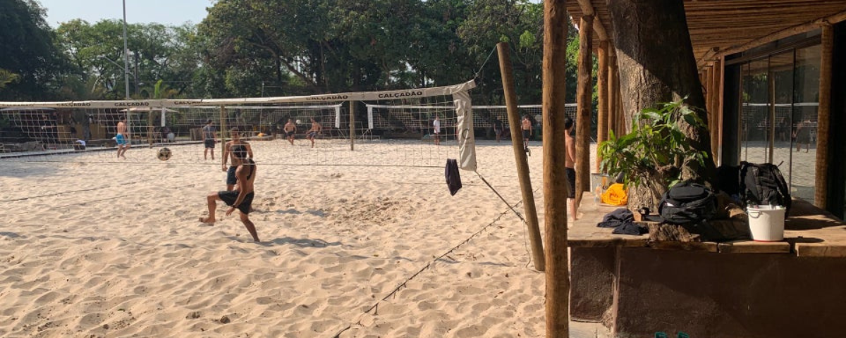 Foto do Botanikafé, com pessoas jogando futevôlei em uma de suas quadras de areia. 