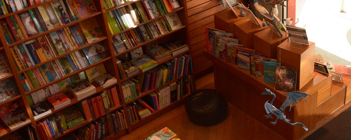 Foto do interior da NoveSete, uma das livrarias em São Paulo, com diversas prateleiras e livros em suas estantes de madeira.