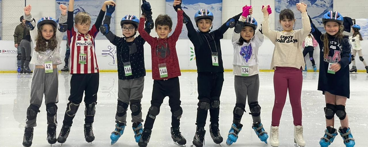 Crianças de mãos dadas em pista de patinação no gelo.