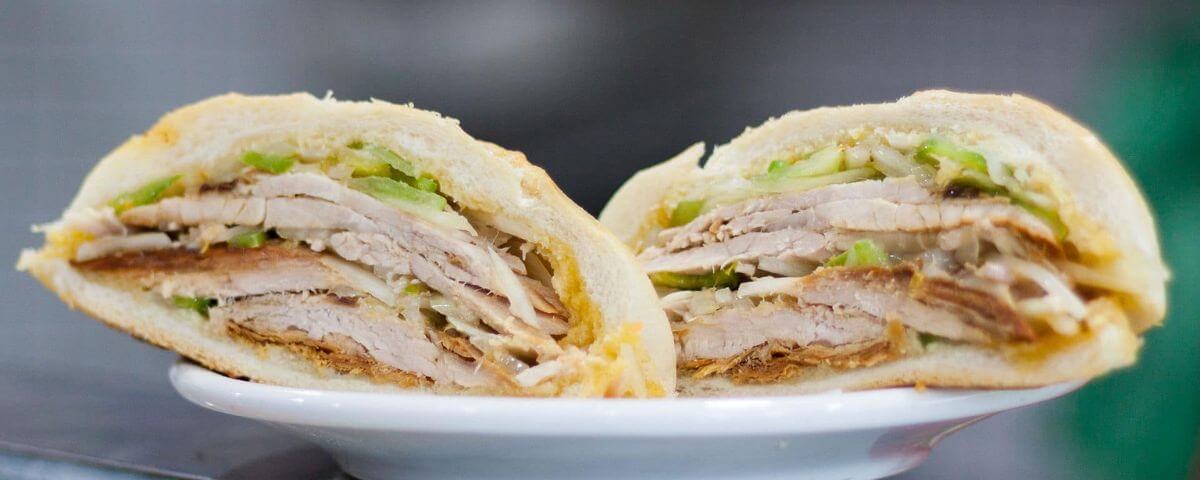 Foto de dois sanduíches de frango no pão branco em cima do prato. 