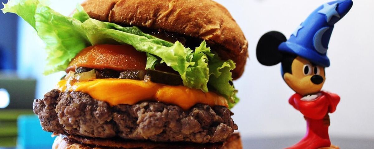No Dia Mundial do Hambúrguer, o Le Burger é uma ótima pedida! Estátua no Mickey Mouse ao lado de um hambúrguer bem servido com queijo, alface, tomate e pão. 