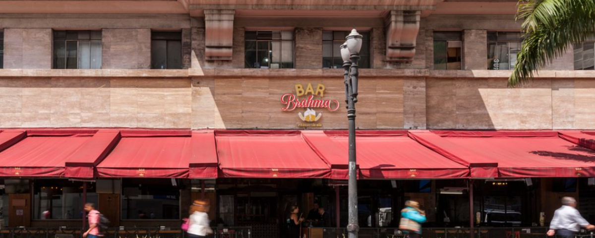 O Bar da Brahma, no centro de SP, tem toldos vermelhos e uma varanda extensa com mesas. 