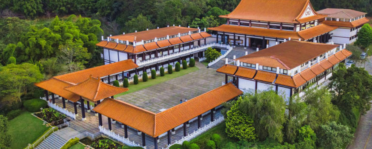 O Templo Zu Lai tem característica de templos budistas, com telhado marrom, detalhes brancos e árvores ao redor. O templo é um ótimo local para praticar meditação em SP. 