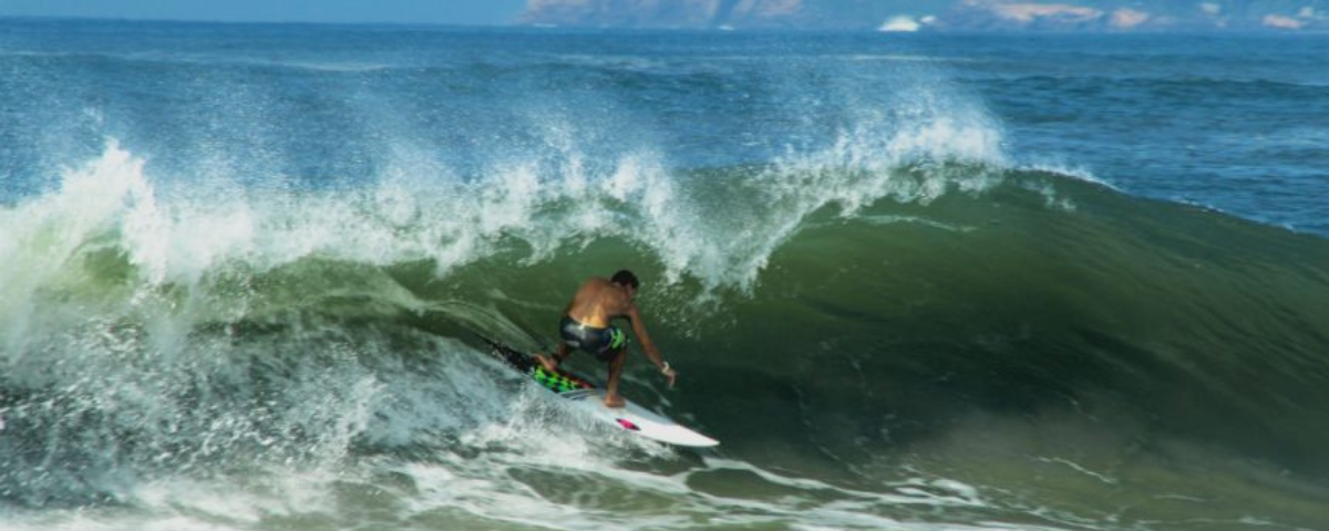 A Praia do Tombo é outro ponto de Surf em SP. Surfista se equilibra em um tubo de onda. 
