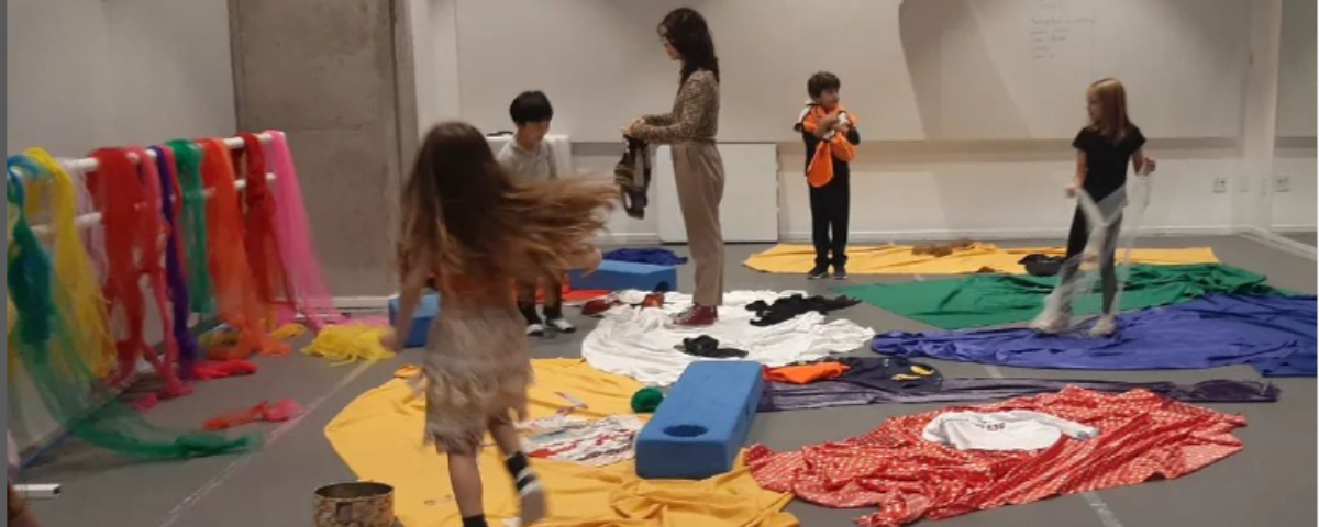 Crianças brincam com tecidos em uma sala espaçosa de uma brinquedoteca em SP. 