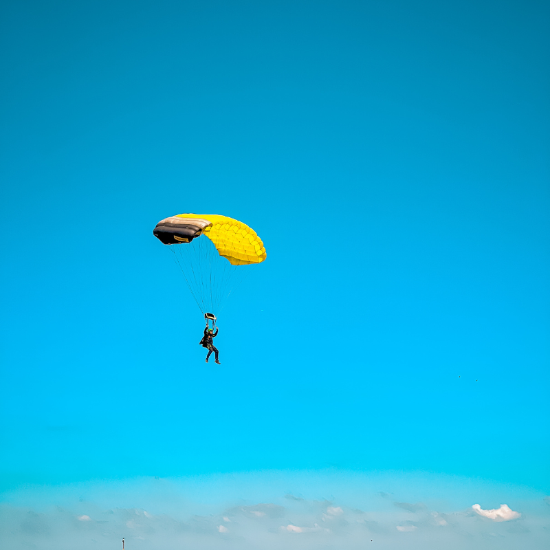 Pessoa saltando de paraquedas na cor amarelo, em um céu sem nuvens, todo azul, na cidade de Boituva. 