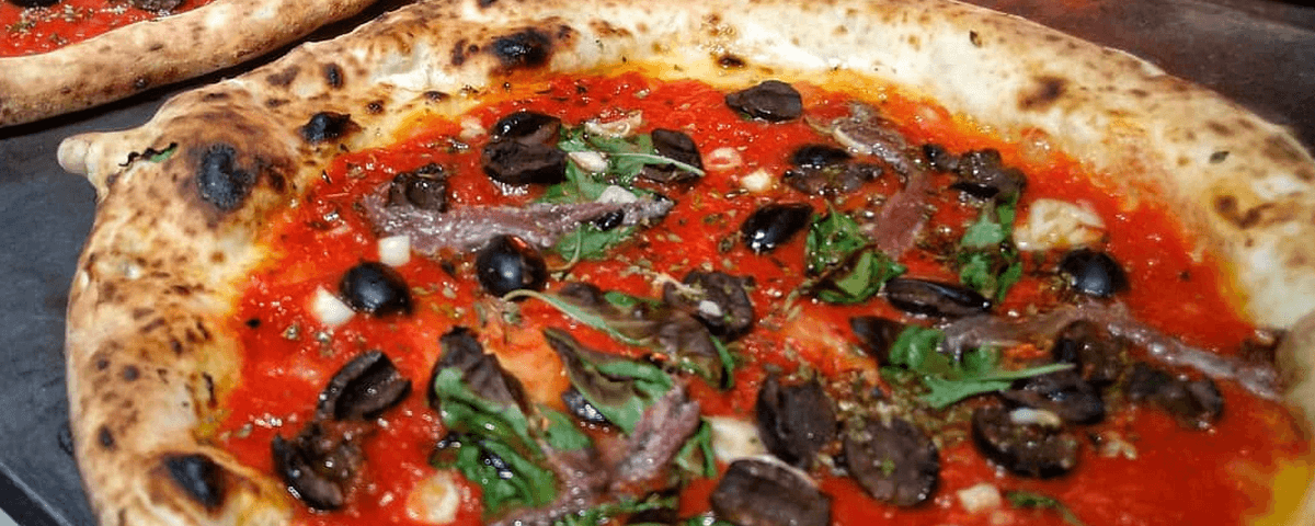 Pizza tipicamente napolitana com muito molho de tomate, azeitonas e folhas de manjericão é servida na Leggera Pizza Napoletana. 