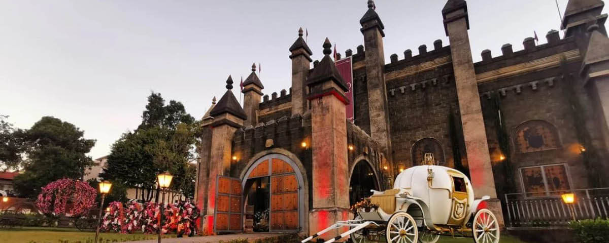 Castelo com uma carruagem branca parada na frente. 