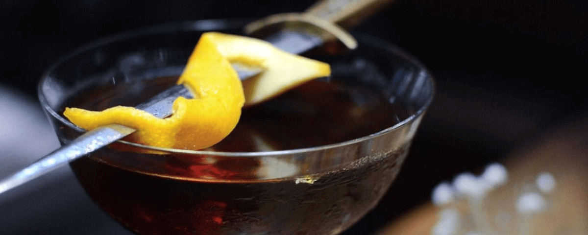 Drink com uma casca de laranja espetada em uma faca e equilibrada em cima de uma taça é servido no Flora Bar, um dos bares diferentes de SP, que tem um ambiente chique e intimista. 
