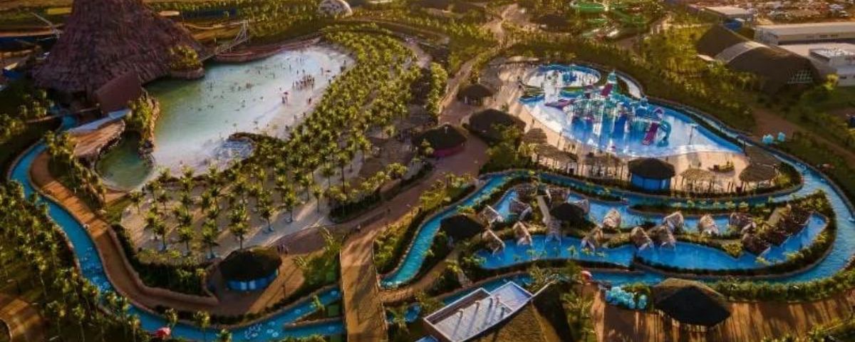 Vista de cima de parque aquático com diversas piscinas e coqueiros. 