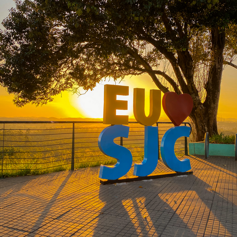 Sol se põe no Mirante do Banhado, com um letreiro escrito "Eu amo SJC".