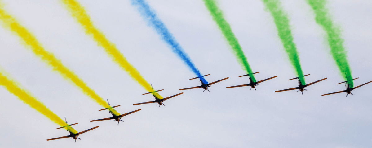 Aviões da Força Aérea Brasileira voam soltando fumaça nas cores verde, azul e amarelo. 