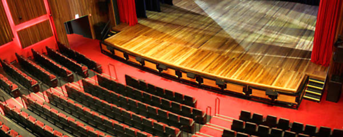 O Teatro Paulo Autran possui uma arquibancada com diversas poltronas e um palco com o chão de madeira. 
