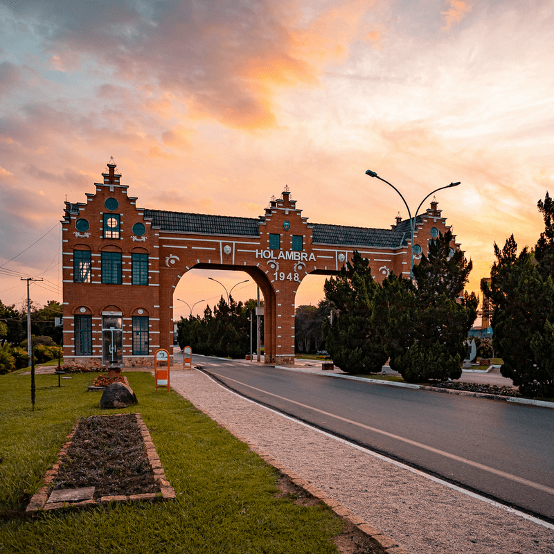 Portal na entrada da cidade de Holambra, na cor marrom com detalhes e o nome da cidade escrito em branco. 