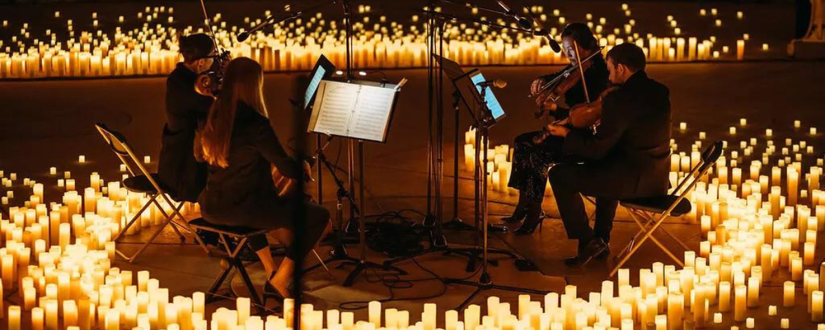 Músicos tocam instrumentos com velas ao redor em um concerto da Candlelight. 