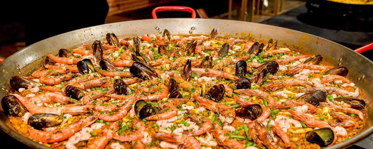 Paella em SP servida com diversos frutos do mar em uma grande panela. 