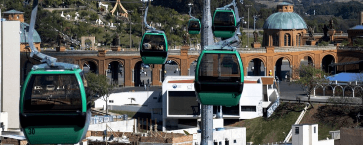 Teleféricos com cabines nas cores verde e preto circulam na cidade de Aparecida. 