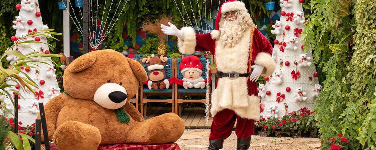 Papai Noel ao lado de um grande urso de pelúcia no Natal 2023 de Holambra. 