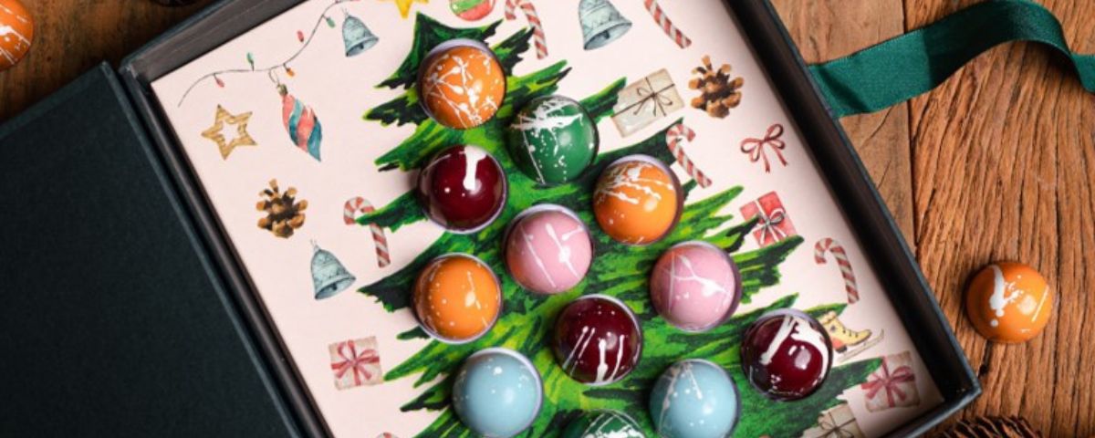 Bolinhas feitas chocolate em caixa com desenho de uma árvore de Natal é uma das opções de sobremesas natalinas. 