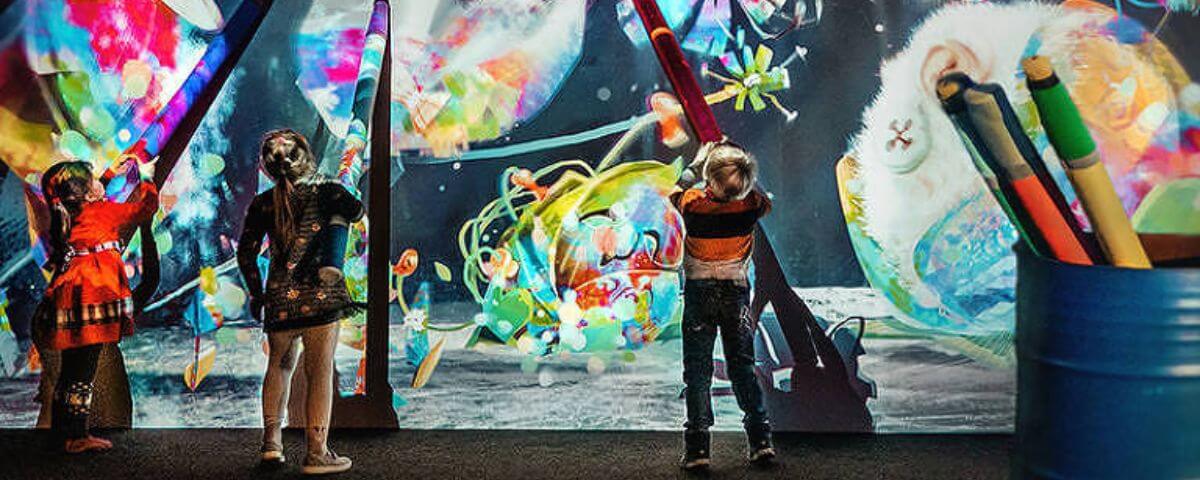 Crianças desenham em mural iluminado no Hello Park, outra opção de passeio para as férias de janeiro. 