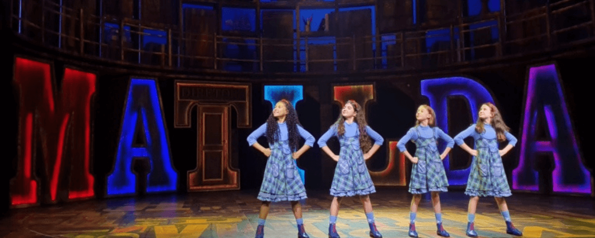 Quatro meninas no palco durante apresentação do musical "Matilda". 