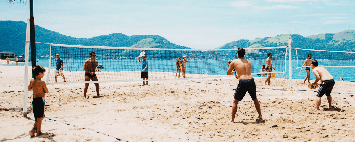 Pessoas jogando beach tennis em uma praia no litoral paulista. 