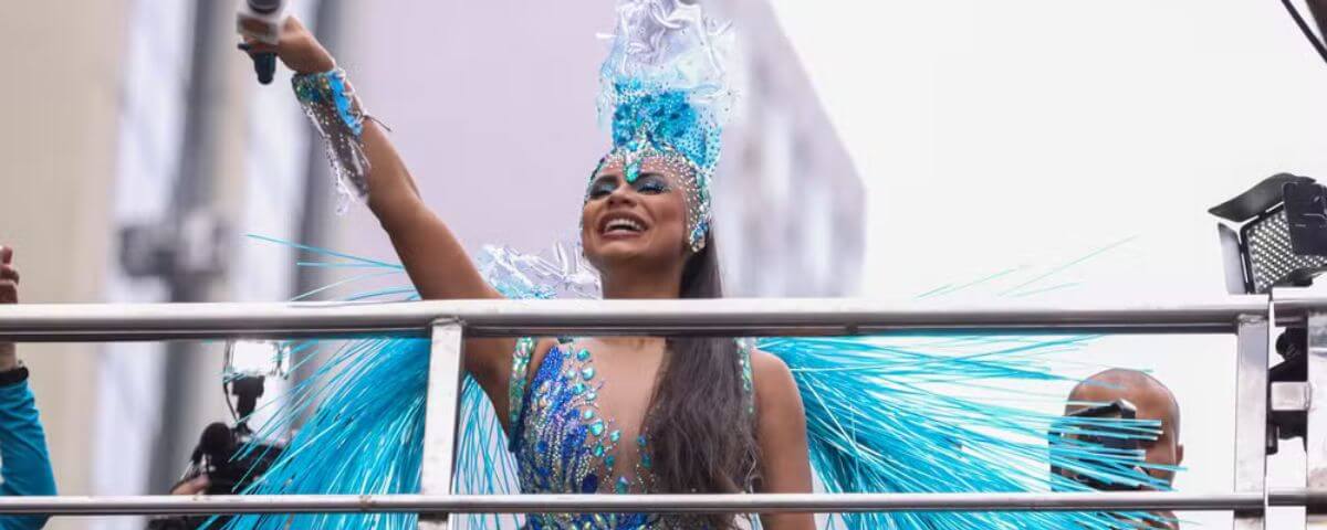 Cantora Lexa usando uma fantasia com tons de azul se apresentando em um dos bloquinhos de carnaval. 