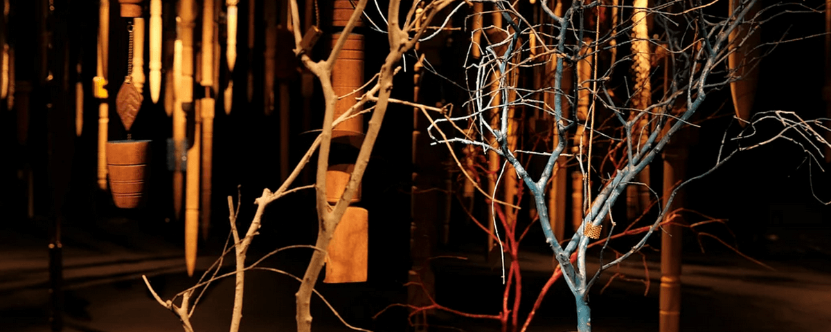 Galhos de árvores em ambiente escuro na exposição "O Mergulho". 