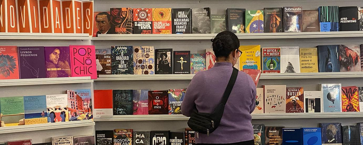 Mulher olha livros em estante de livraria localizada no edifício Copan. 