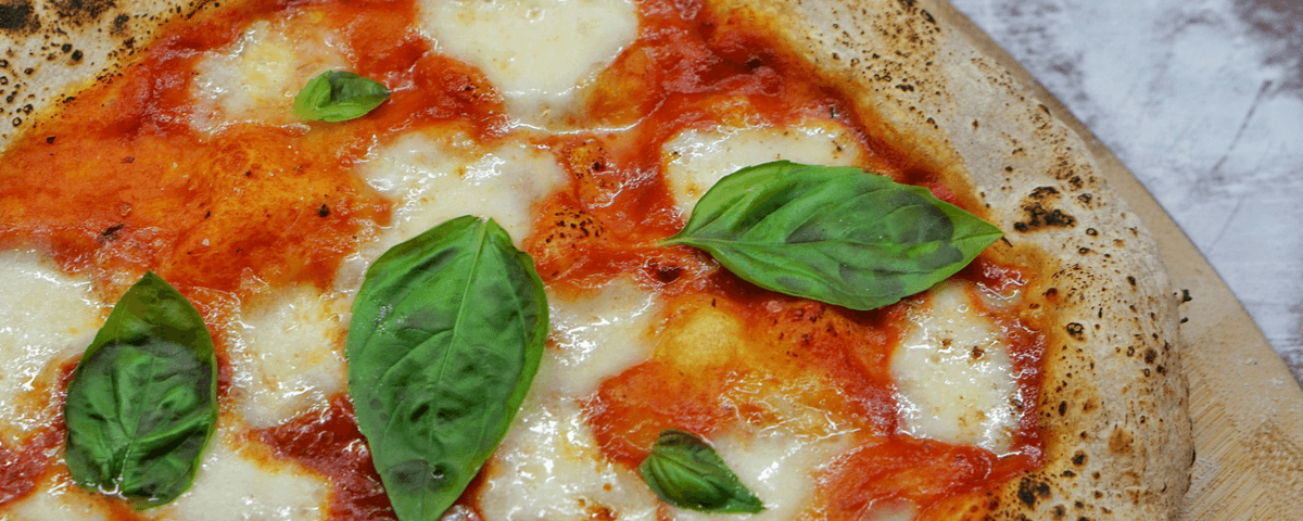 Pizza marguerita com queijo, molho de tomate e folhas de manjericão fresco. 