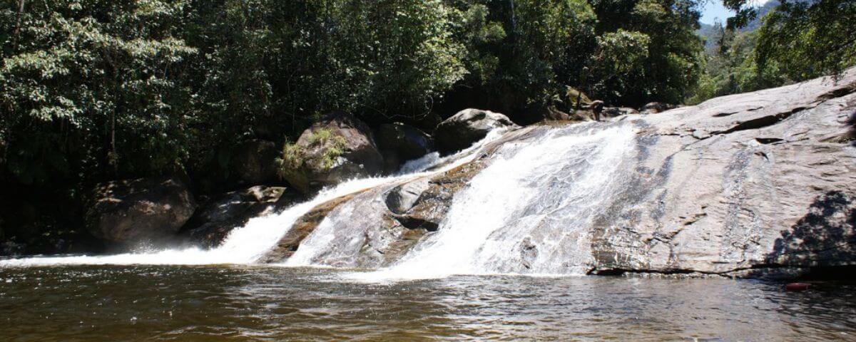 Água caindo por entre as pedras de uma cachoeira. 
