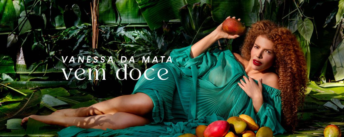 Cantora Vanessa da Mata deitada, segurando uma manga, na capa do seu álbum "Vem Doce". A cantora está na agenda dos shows em abril em SP. 