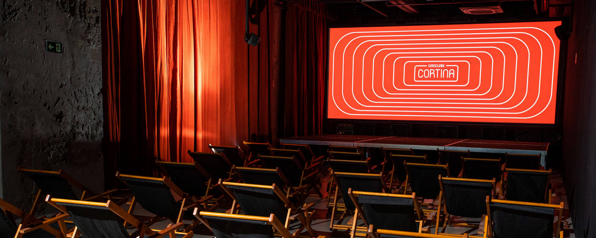 Cadeiras de pano e tela para ver filme no Cineclube Cortina, um local perfeito para a programação pipoca e cinema. 