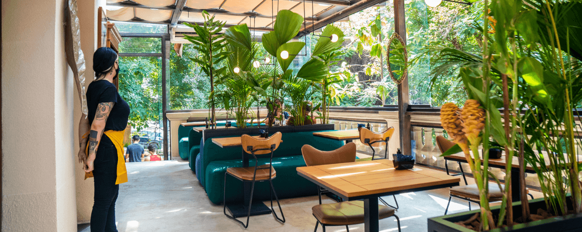 O Mug Café possui mesas ao ar livre e diversas plantas ao redor. A cafeteria é uma ótima opção para celebrar o Dia Mundial do Café. 