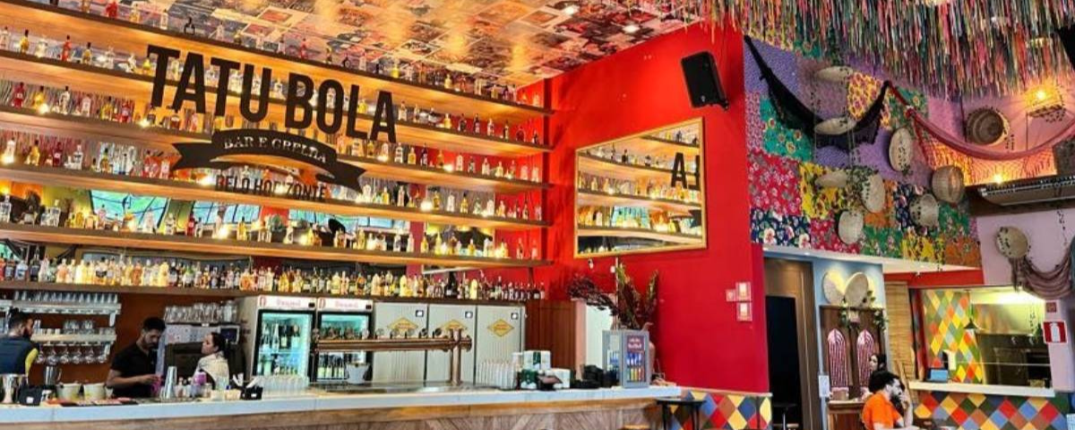 Salão do bar Tatu Bola, com decoração colorida e diversas garrafas de bebidas na parede, uma ótima opção para celebrar o Dia do Amigo 2024.