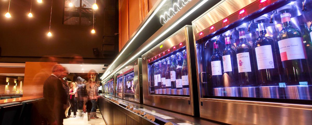 Diversas garrafas em uma geladeira comprida em um bar de vinho. 