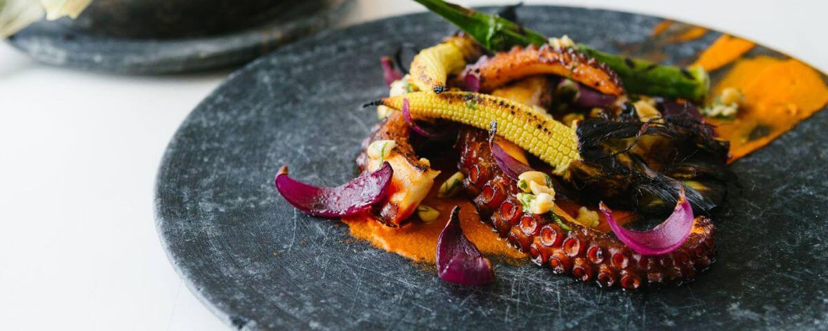 Prato com polvo e legumes na brasa do restaurante Maní. Peça em casa e se surpreenda! 