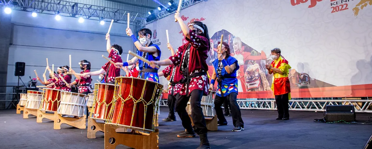 Pessoas em trajes típicos japoneses tocando tambores. 